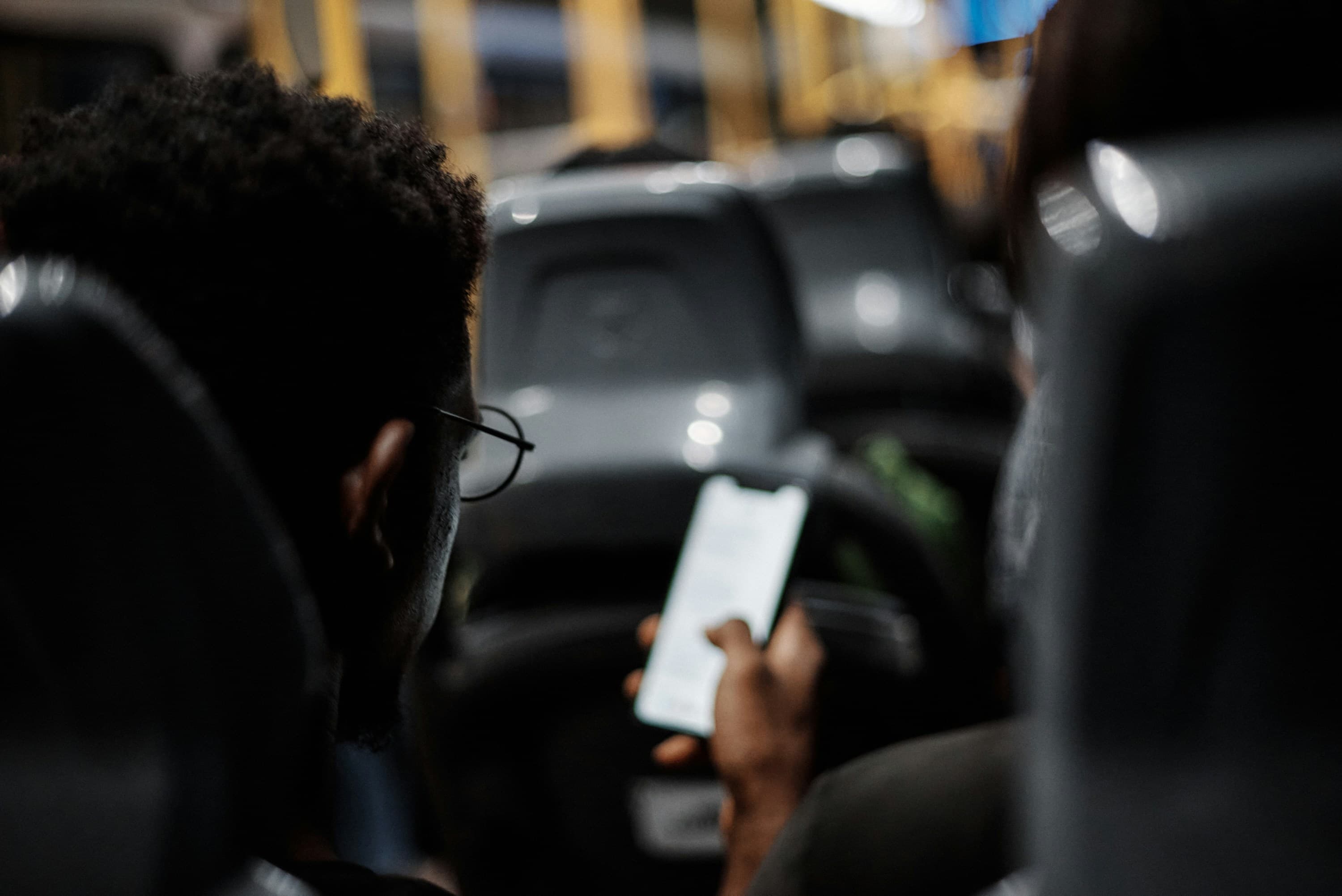Pessoa mexendo no celular dentro de um carro à noite